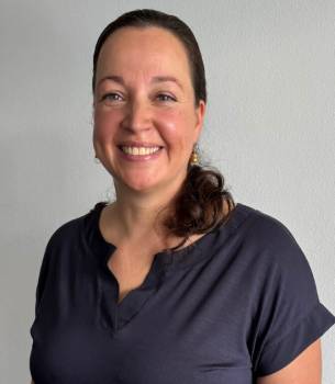 Eine Frau mit seitlichen Pferdeschwanz lacht in die Kamera.